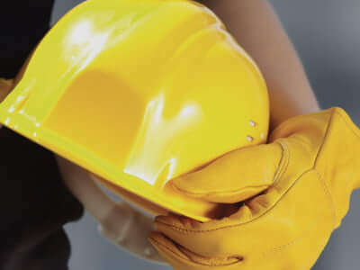 Gloved hand holds yellow hard hat.