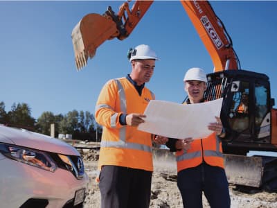 Two workers survey construction plans on a job site