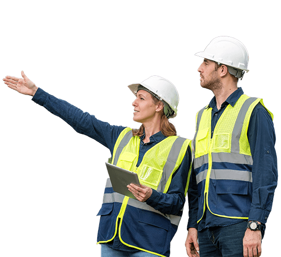 Two utility workers on a jobsite wearing hard hats and safety vests.