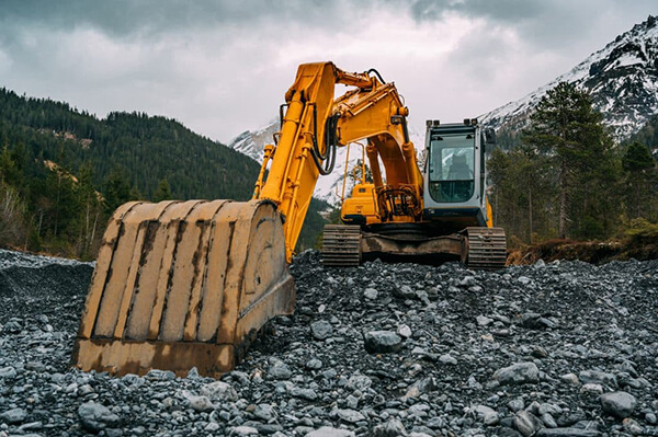 Construction worker operating a digger excavates land.